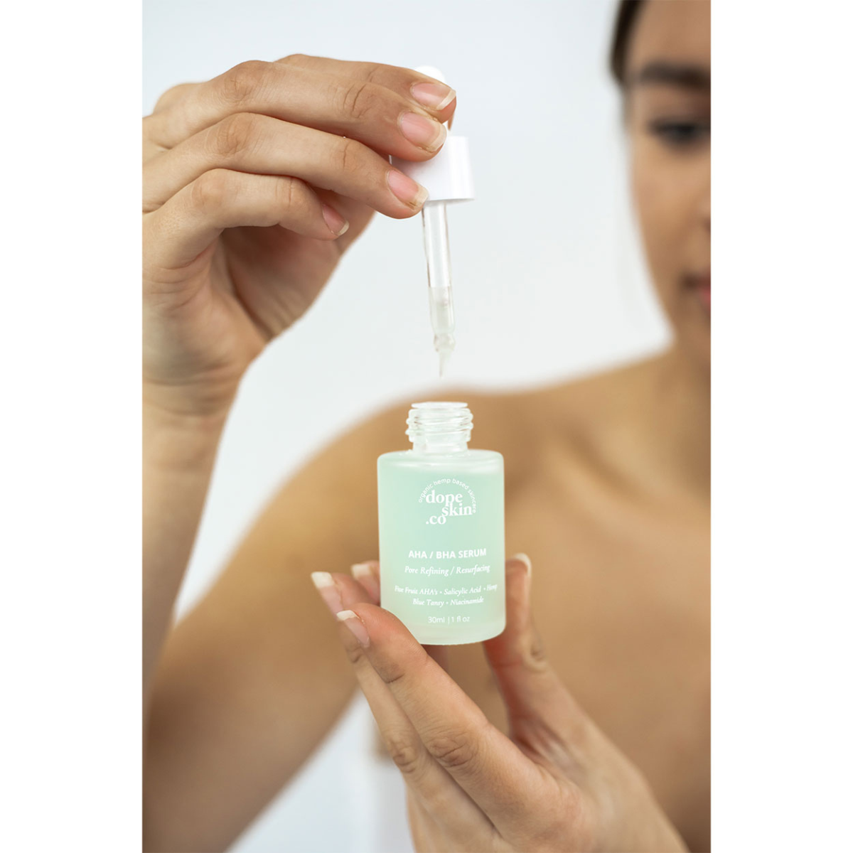 Image of woman holding open bottle of Dope Skin Co AHA BHA Resurfacing serum