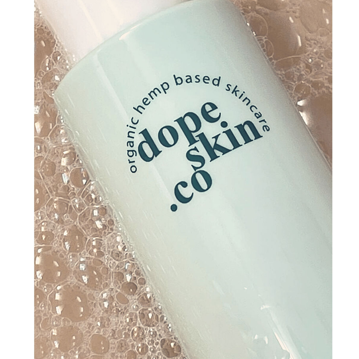 Close up image of Dope Skin Co Antioxidant Gel Cleanser bottle lying in bubbles