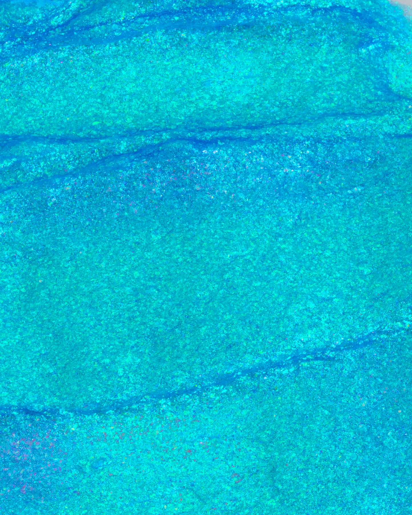 Close-up of blue and green glittery paint swatch texture