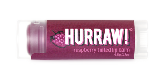 A stick of Hurraw! Raspberry Tinted Lip Balm with a purple label and a depiction of a raspberry fruit.
