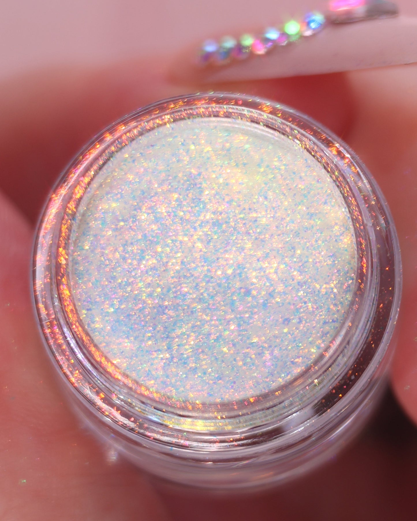 Jar of glittery eyeshadow powder held between fingers