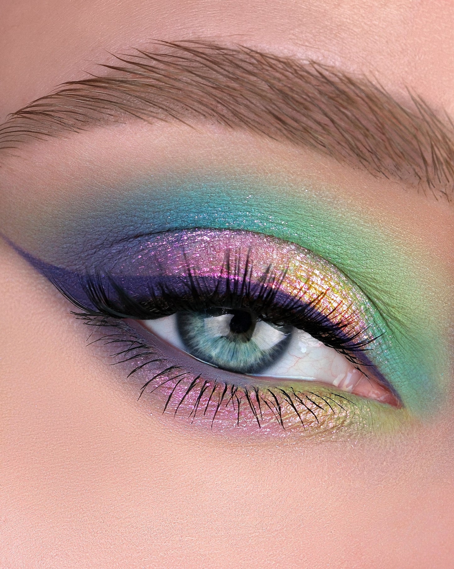 Close-up of a colorful eye makeup with blue, green, and purple shades using Rockabye Baby