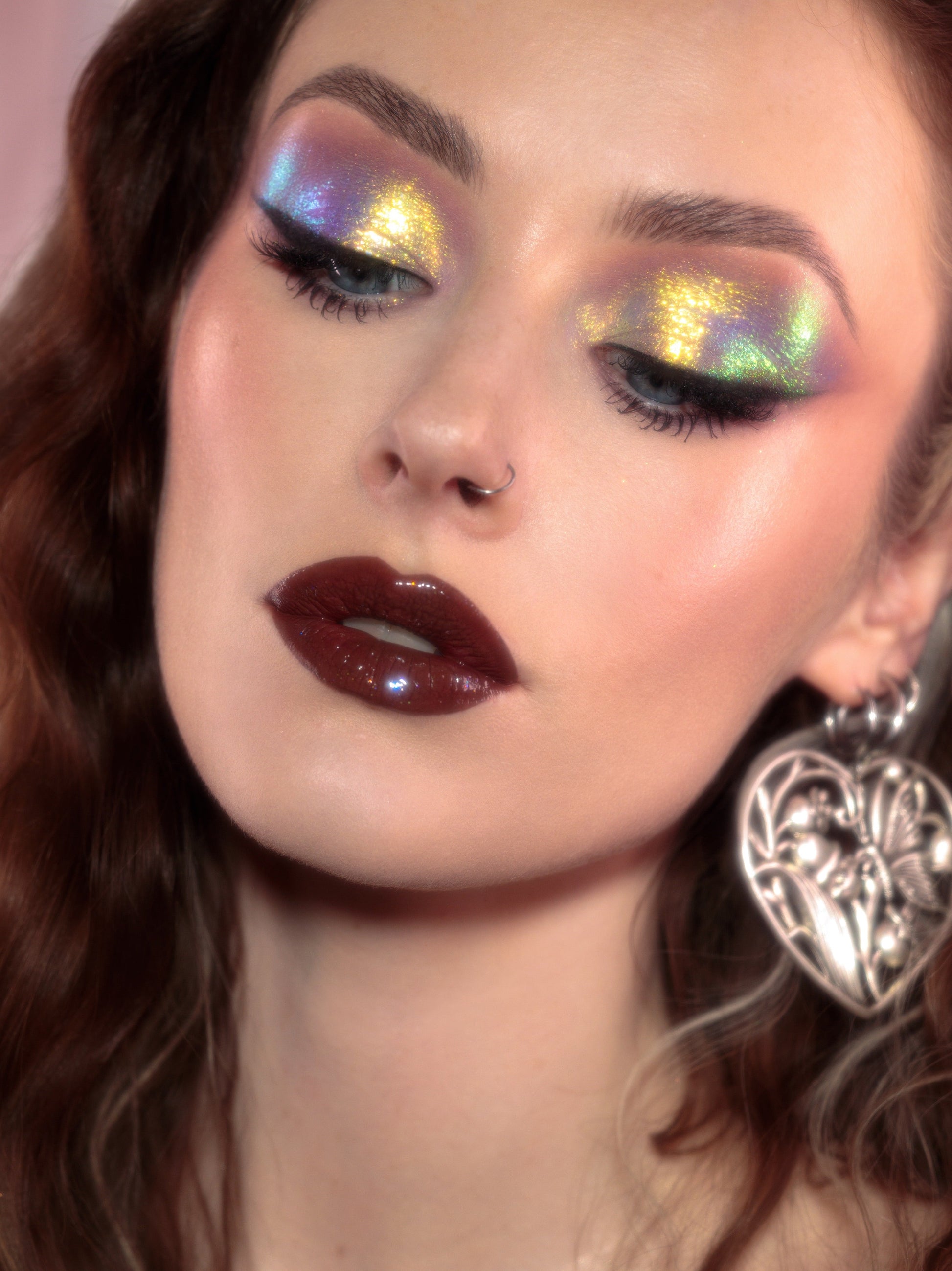 Close-up of a person with colorful eye makeup and dark lipstick.