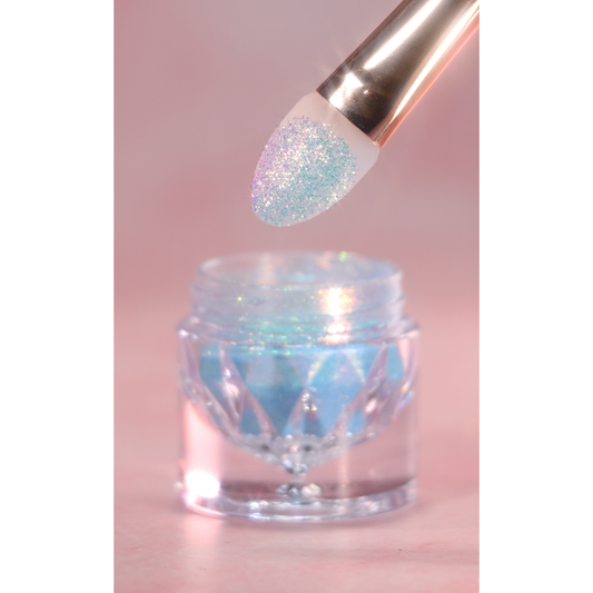 Glittery makeup brush dipping into a jar of glitter on a pink background