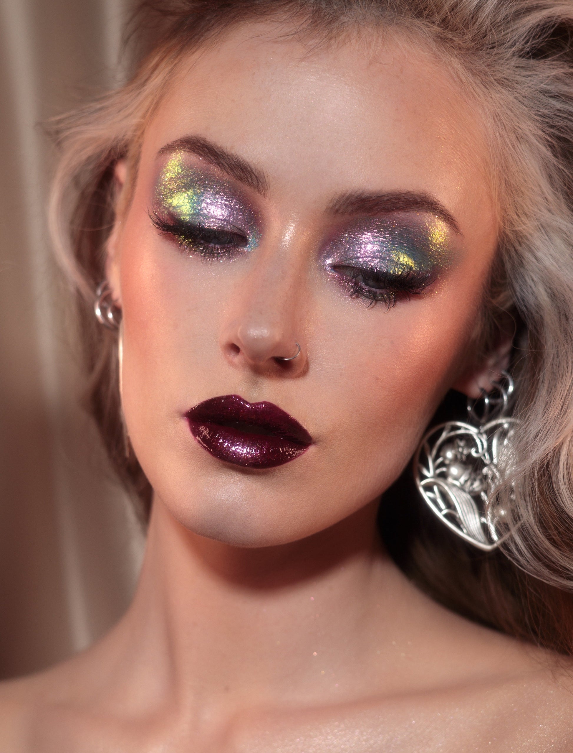 Close-up of a person with dramatic makeup and earrings against a neutral background