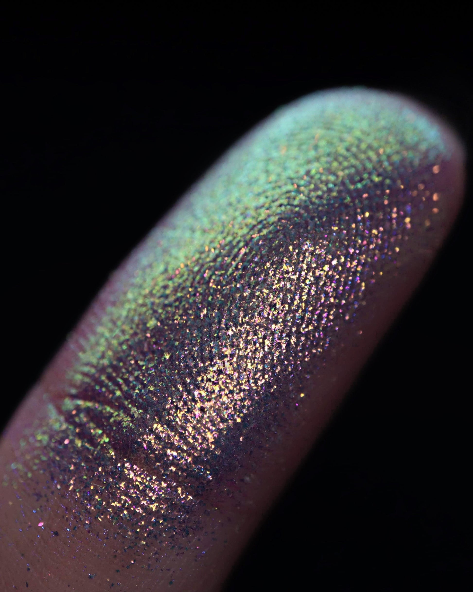 Close-up of a multicolored glittery powder on a finger with a black background
