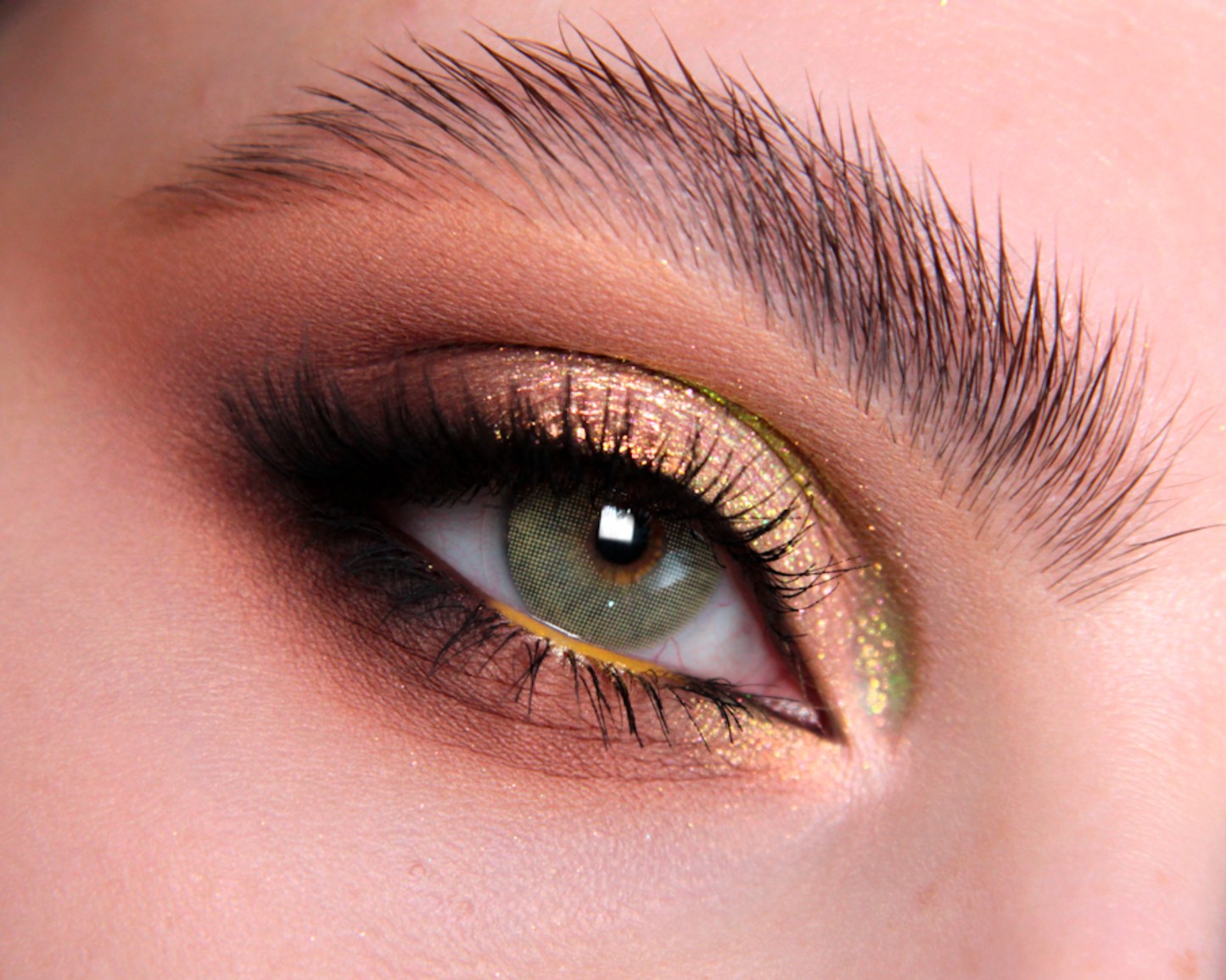 Close-up of a person's eye with green and gold makeup