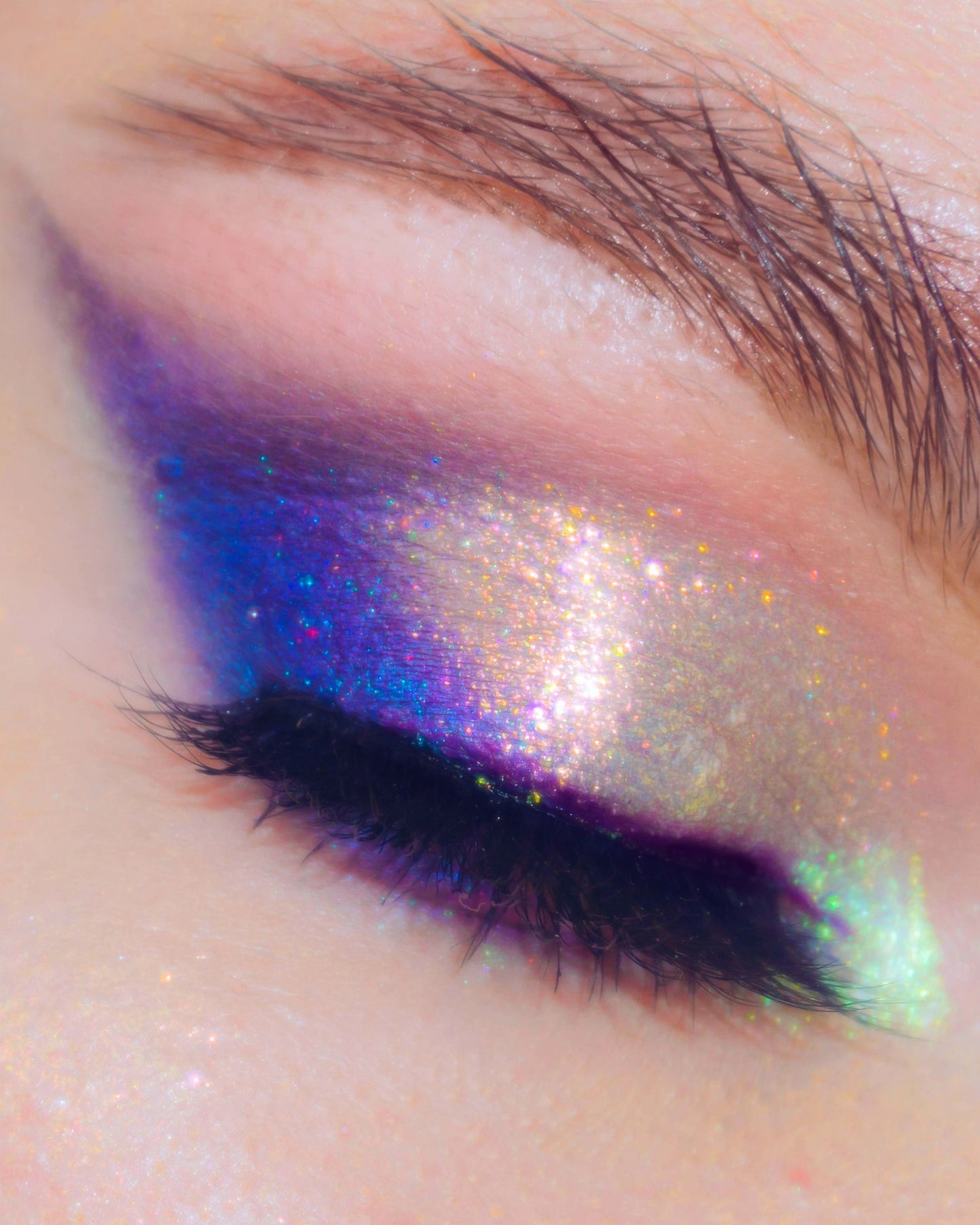 Close-up of a colorful eye makeup with blue, purple, and green shades.