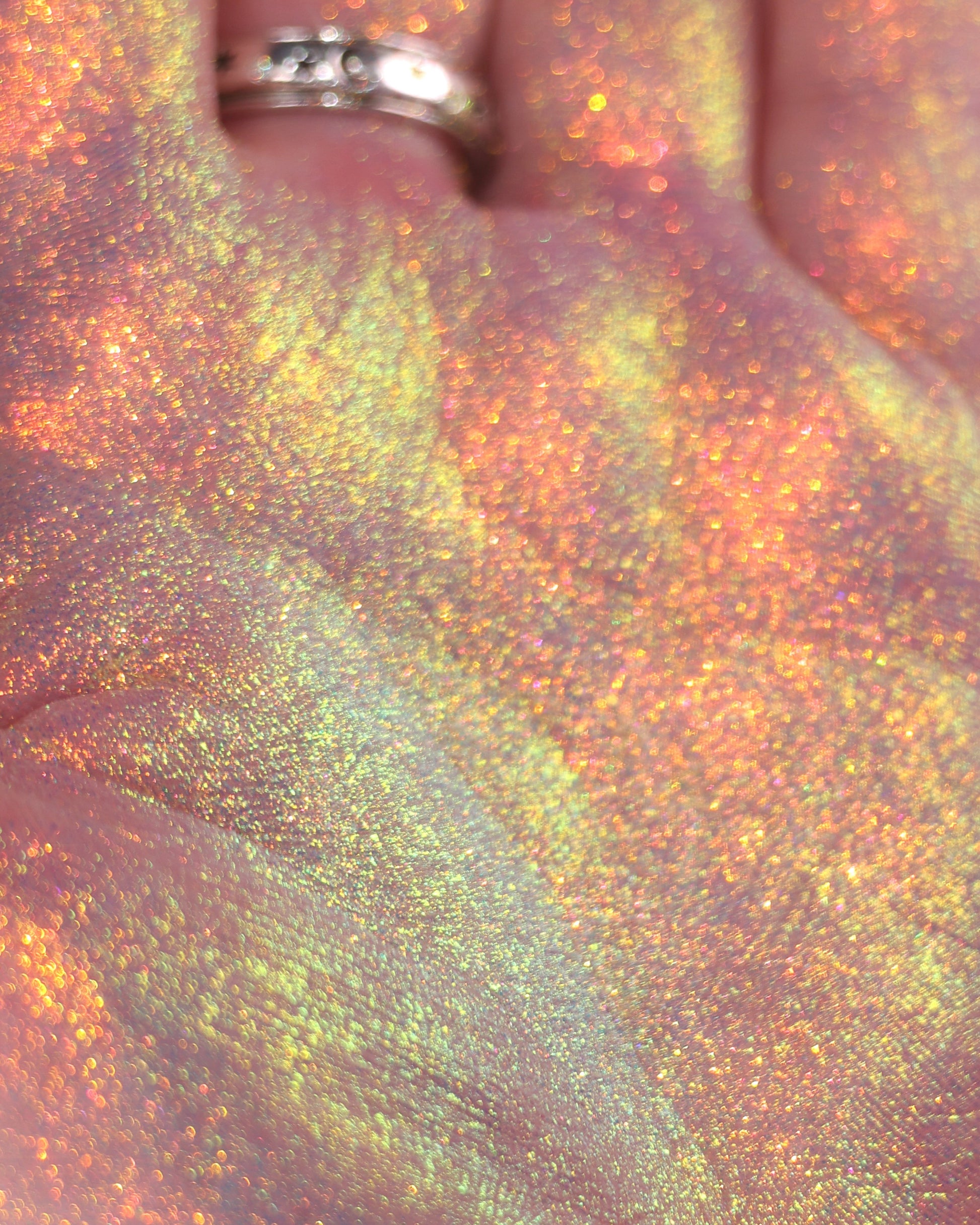 Close-up of a hand holding a colourful, glittery makeup product.