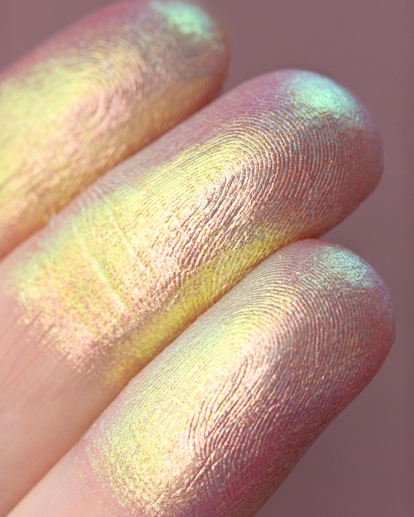 Close-up of a hand with colorful makeup on the fingers against a pink background