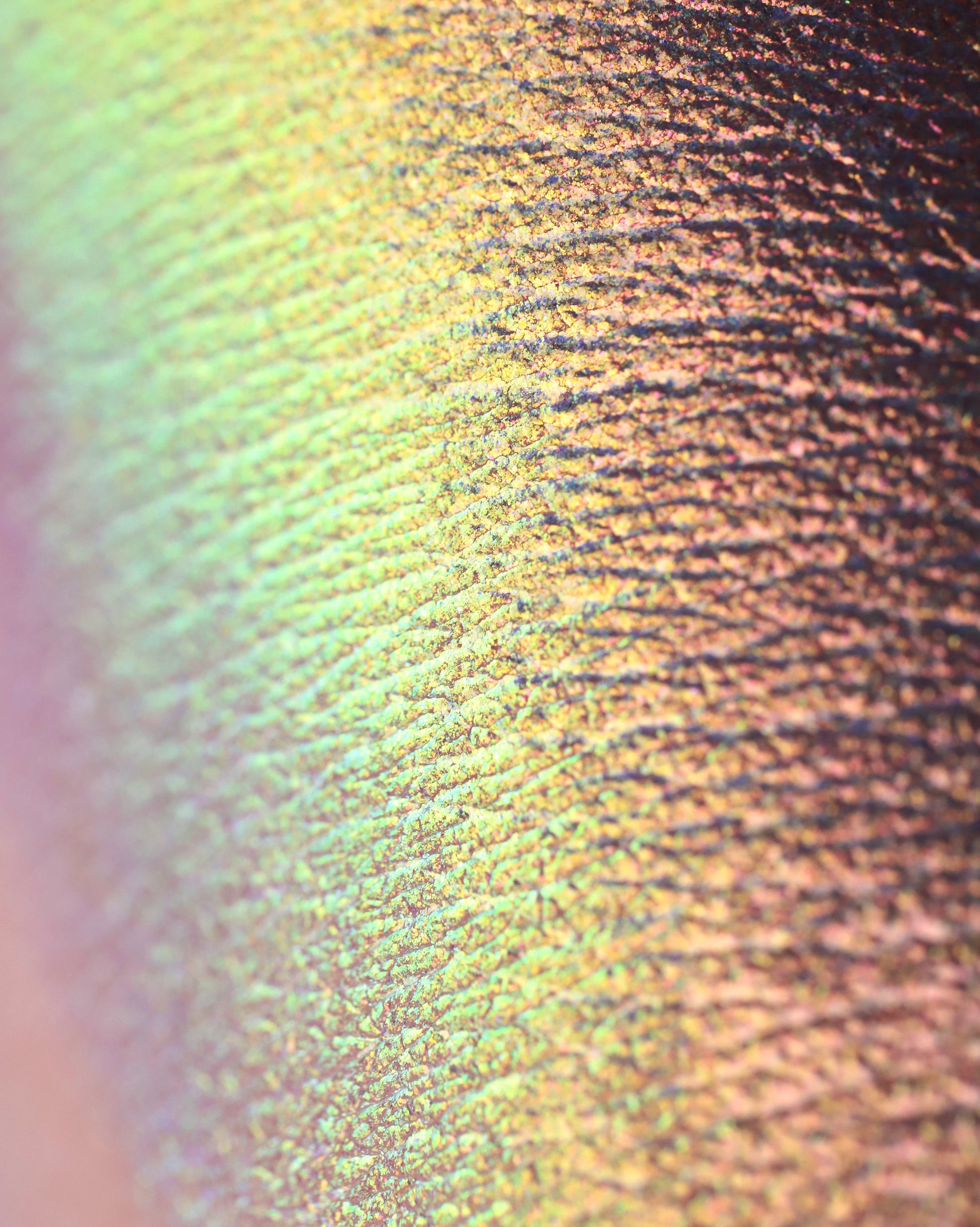 Close-up of a textured swatch of iridescent eyeshadow powder on hand